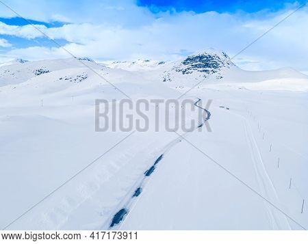 Lonely Frozen Road Winding Through A Snow Covered Mountain Landscape On A Cold Winters Day.