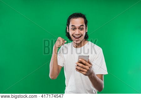 Asian Man With Long Black Hair Holding And Look Handphone With Happiness Expression While Raising On