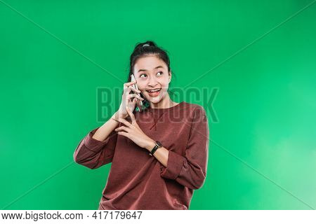 Beautiful Young Asian Woman Is Talking On The Phone Smiling Faintly With Someone While Looking Up