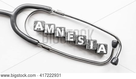 Stone Block Form Word Amnesia With Stethoscope. White Background. Medical Concept. Unusual Memory Lo