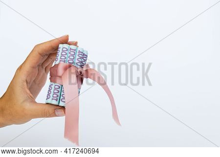 Ukrainian Money Wrapped With A Gift Ribbon In A Hand.