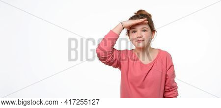 Portrait Of A Curious Young Girl In Pink Casual Sweatshirt Looking Far Away With Hand At Her Forehea