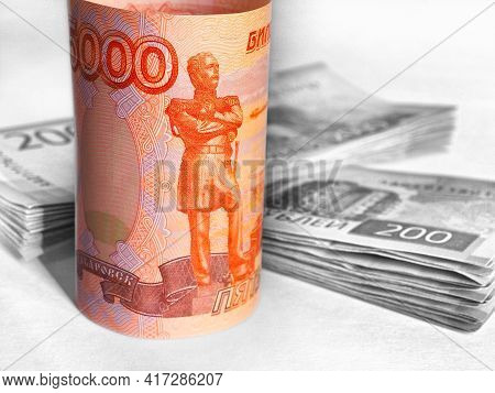 Brightly Lit Russian Banknote 5000 Rubles On A Dark Background. The Background Includes Stacks Of 20