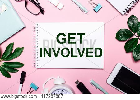 Get Involved Is Written In A White Notebook On A Pink Background Surrounded By Business Accessories 