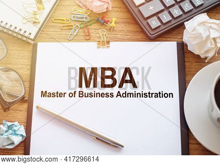 On A Wooden Table There Is An Office Sheet Of Paper With The Text Mba - Master Of Business Administr