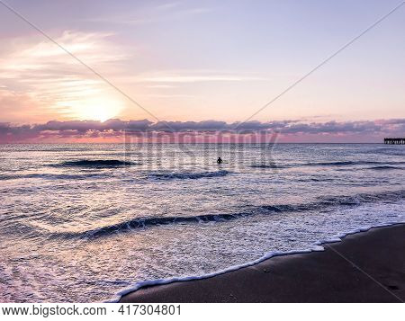 One Person Swimming In The Ocean At Dawn