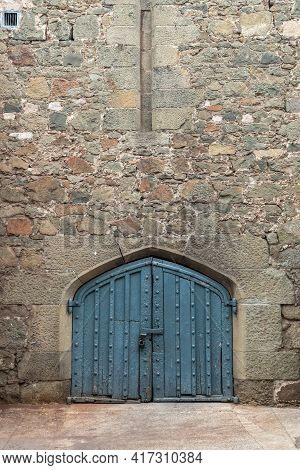 Ancient Stone Wall With A Gate In The Old Castle. Wooden Gate Of A Medieval Castle