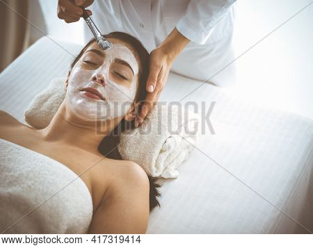 Beautiful Brunette Woman Enjoying Applying Cosmetic Mask With Closed Eyes Comfortable And Blissful. 