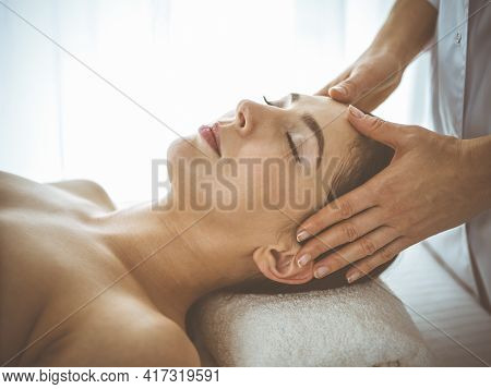 Beautiful Brunette Woman Enjoying Facial Massage With Closed Eyes Comfortable And Blissful. Relaxing