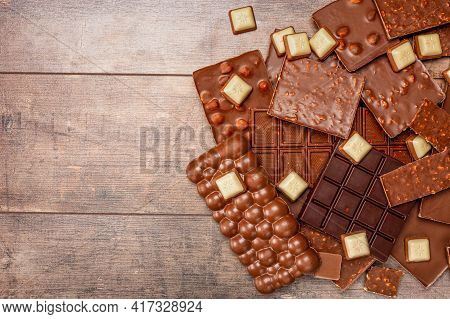 Top View Of Pieces Of Chocolate Bar With Chocolate Chips On Rustic Wooden Table Background. Chocolat
