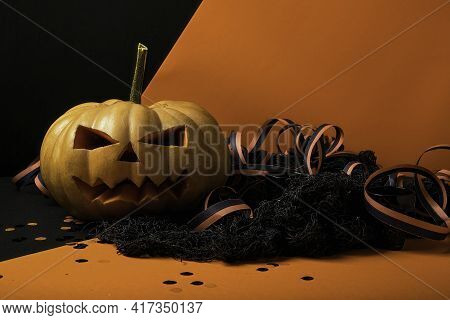 Pumpkin With Glowing Eyes And A Skull On Wooden Background. Sinister Halloween.