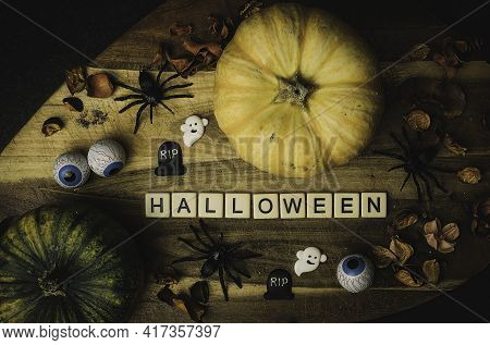 Pumpkin With Glowing Eyes And A Skull On Wooden Background. Sinister Halloween.