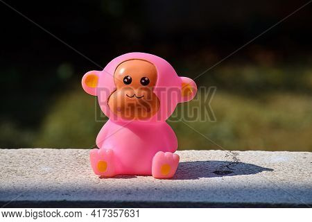 Stock Photo Of Cute Pink Color Baby Monkey Toy Kept On Wall Under Bright Sunlight On Blur Background
