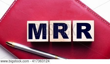 Mrr Made Up Of Wooden Cubes That Stand On A Burgundy Notebook Near The Pen. Business Concept