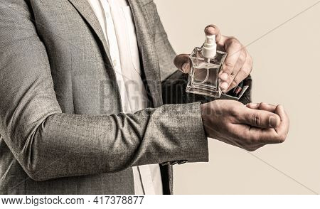 Men Perfume In The Hand On Suit Background. Man In Formal Suit, Bottle Of Perfume, Closeup. Fragranc