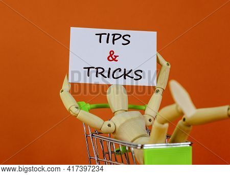 Tips And Tricks Symbol. White Paper. Words 'tips And Tricks'. Miniature Shopcart, Wooden Human. Beau