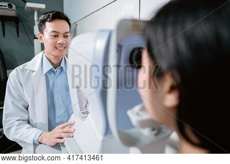 A Doctor Is Examining A Female Patient Using An Eye Computer