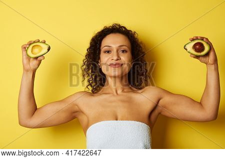 Young Curly And Muscular Build African American Woman Wrapped In A Bath Towel Holding Two Halves Of 