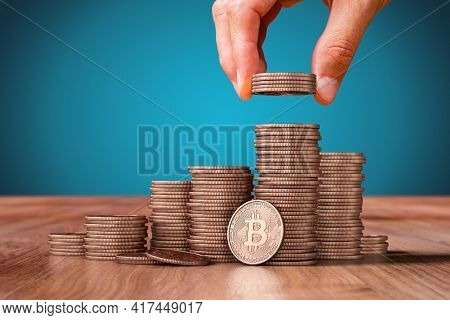 Bitcoin Cryptocurrency Save Money Concept.  Hand With Bitcoin Coins Giving On Mound Of Bitcoins. 

C