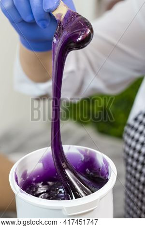 Closeup Of Female Beautician Hands Mixing Liquid Colorful Wax In Plastic Container For  Sugaring Pro