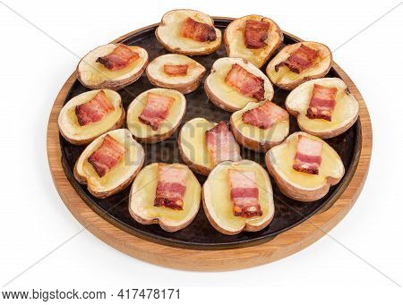 Potato Halves In Their Skins Baked With Bacon Slices On A Round Baking Sheet On A White Background