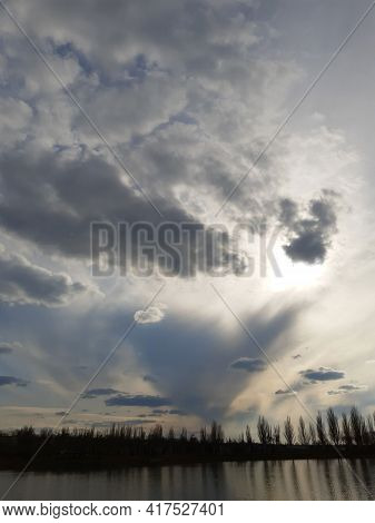 The Sun's Rays Make Their Way Through The Spring Clouds At Sunset Over The City Lake.