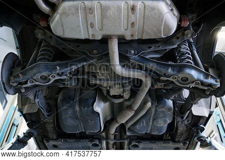A Car In A Car Service Is Lifted On A Lift For Repair. Bottom View Of The Car. Vehicle Underbody, Re