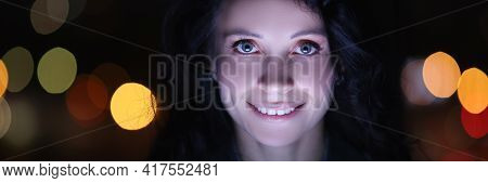 Portrait Of Brunette Woman At Laptop At Night Against Background Of Garlands