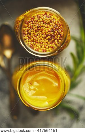 Two kinds of mustard. Frensh with whole seeds and honey served in glass jars