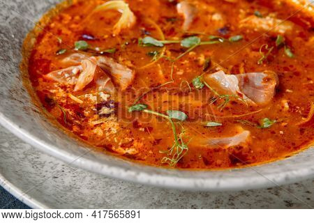 Russian cuisine - Solyanka Soup on dark textured table. Spicy and sour soup with meat slice and vegetables. Ceramic bowl on dark background
