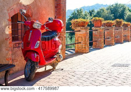 Pienza, Italy - October 16, 2017: Red Vespa Parked On Old Cozy Street In Italy. Vespa On Narrow Old 