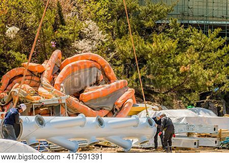 Men Moving Large Industrial Pipe At Construction Site.