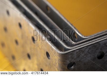 Stack Of Construction Perforated Steel Angle Brackets Close Up. Low Depth Of Field Photography