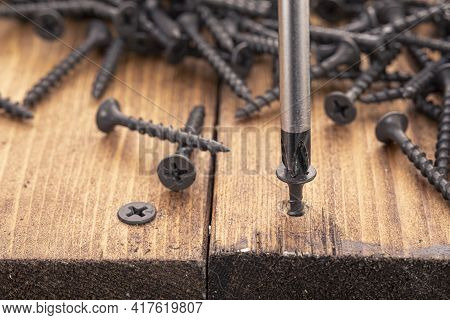 A Screwdriver And Screw On A Wooden Background. Screwdriver Of Chromium Vanadium Steel. Construction