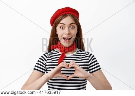 Cute Young Woman In French Berret, Showing Heart Sign And Smile With Amazement, Say I Love You, Stan