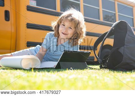 Portrait Of Smart Schoolboy Writing Outdoor In School Park And Doing Homework.