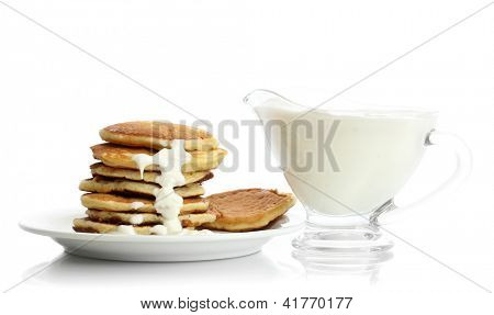 หวาน pancakes บนแผ่นกับนมข้นที่แยกต่างหากบนพื้นสีขาว