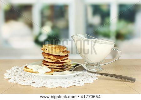 หวาน pancakes บนแผ่น ด้วยครีมเปรี้ยวบนโต๊ะในห้องครัว