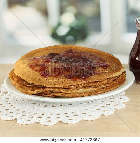 หวาน pancakes บนแผ่นกับแยมบนโต๊ะในห้องครัว
