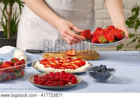 Woman Baker Stacks Strawberries On Meringue Strawberry Cake Base. Homemade Strawberries Cake Made Fr