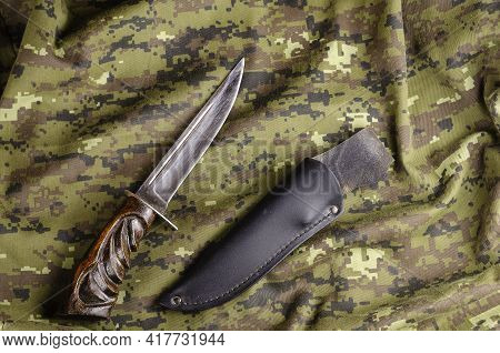 Knife With Wooden Handle And Leather Scabbard On Camouflage Fabric. Extracted From The Scabbard Is A