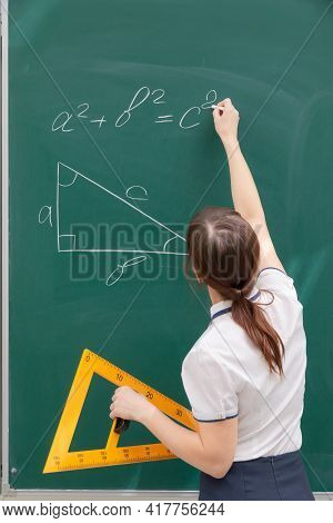 School Teacher Young Woman In The Class At The Blackboard Draws A Triangle With A Ruler. Portrait. C