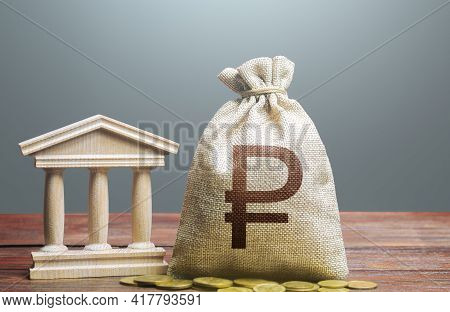Russian Ruble Money Bag And Bank / Government Building. Tax Collection And Budgeting. Monetary Polic