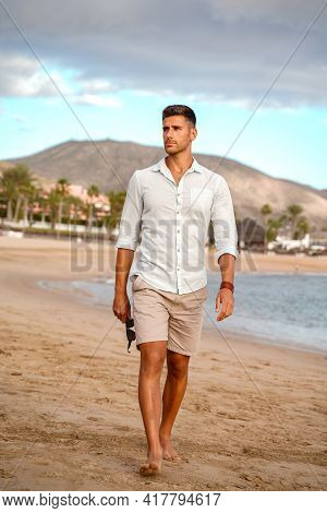 Handsome Fashionable Young Man Walking On The Beach, Relaxing. Summer Vibes. Fashion Photo Of Italin