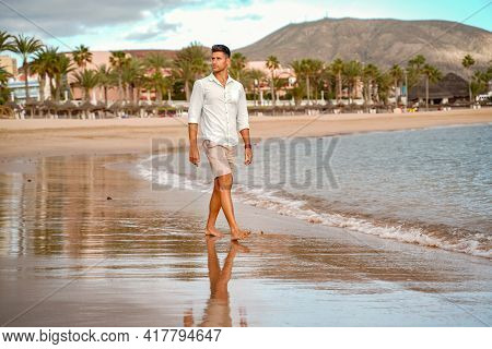 Handsome Fashionable Young Man Walking On The Beach, Relaxing. Summer Vibes. Fashion Photo Of Italin