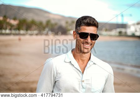 Handsome Fashionable Young Man Walking On The Beach, Relaxing. Summer Vibes. Fashion Photo Of Italin
