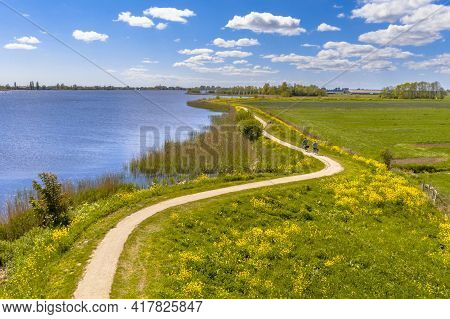 Aerial Springtime Scene Of Dutch River Near Boornzwaag. Cycling Track On Dike Meandering Throug Pold
