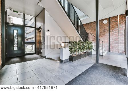 Staircase And Elevator Located Near Door And Brick Wall In Hall Of Contemporary Apartment Building