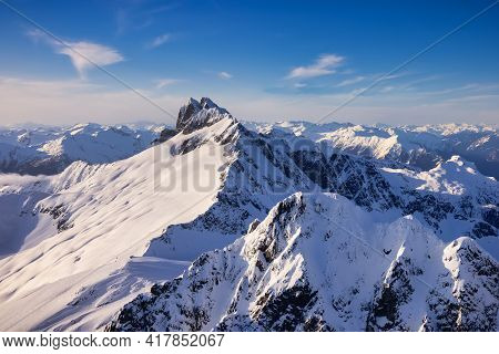 Aerial View From Airplane Of Blue Snow Covered Canadian Mountain Landscape In Winter. Bright Sunny B