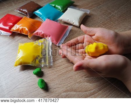 Children's Hands Crumple Soft Plasticine. Packages With Plasticine Are On The Table. Creativity For
